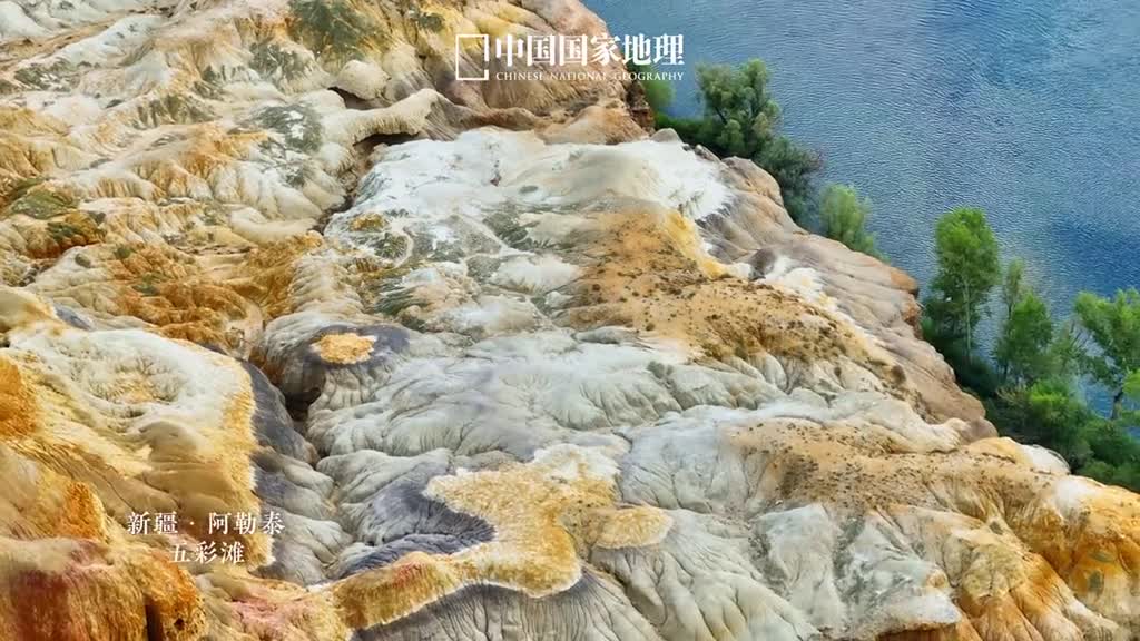 这就是地理书上的彩丘五彩滩地处准噶尔盆地西北部额尔齐斯河之畔与河对岸青葱翠绿的景观遥相辉映这里气候干燥狂风的光顾加上河流的侵蚀雕琢出了一片充满神秘色彩的魔鬼城岩层自红层之上发育起来在多样的沉积环境之下幻化出种种异彩如同干旱区的彩虹铺展在西北大地上