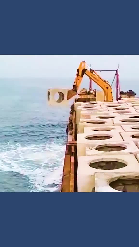 货船行驶在海上把带窟窿的混凝土扔进海里建立人工鱼礁