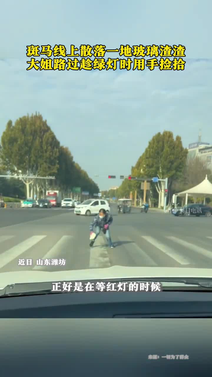斑马线上散落一地玻璃渣渣大姐路过趁绿灯时用手捡拾