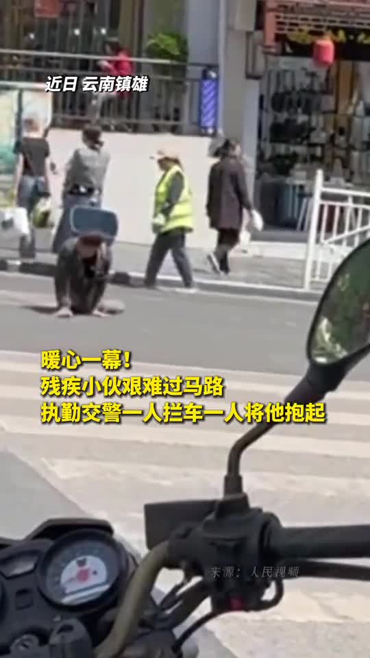 暖心一幕残疾小伙艰难过马路执勤交警一人拦车一人将他抱起