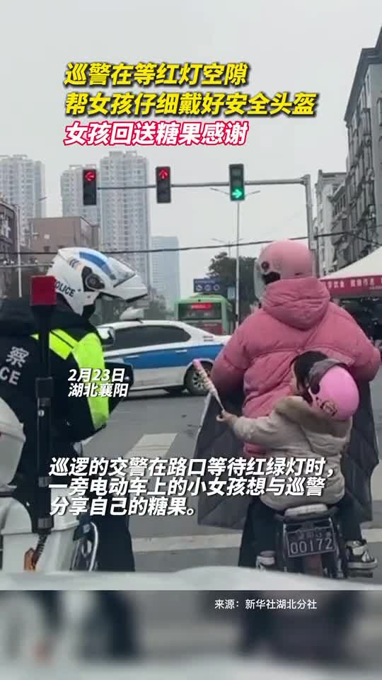 巡警在等红灯空隙帮女孩仔细戴好安全头盔女孩回送糖果感谢