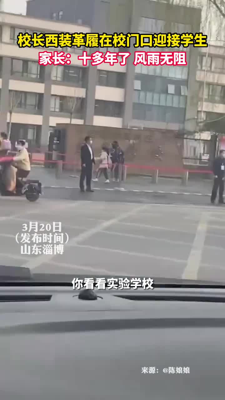 校长西装革履在校门口迎接学生家长十多年了风雨无阻