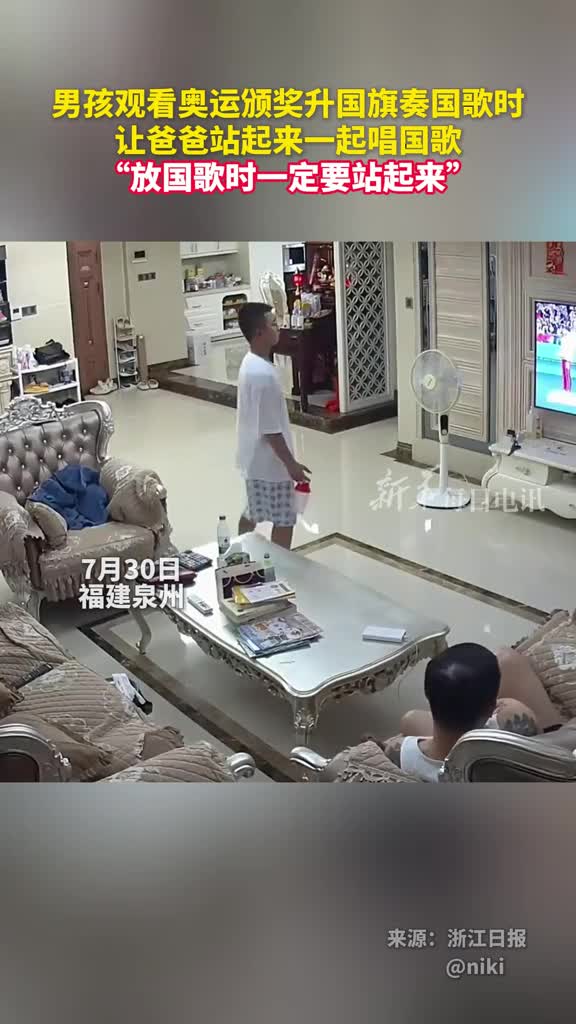 男孩观看奥运颁奖升国旗奏国歌时让爸爸站起来一起唱国歌放国歌时一定要站起来