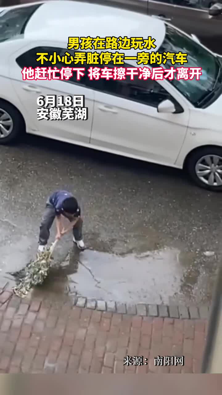 男孩在路边玩水不小心弄脏停在一旁的汽车他赶忙停下将车擦干净后才离开