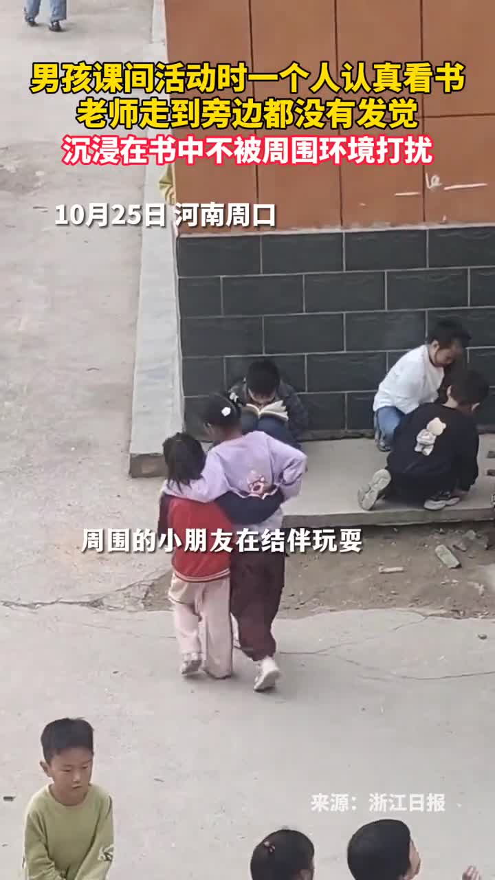 男孩课间活动时一个人认真看书老师走到旁边都没有发觉沉浸在书中不被周围环境打扰