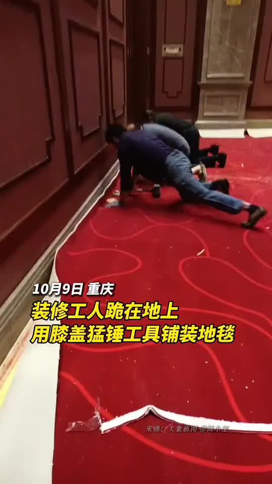 装修工人跪在地上用膝盖猛锤工具铺装地毯