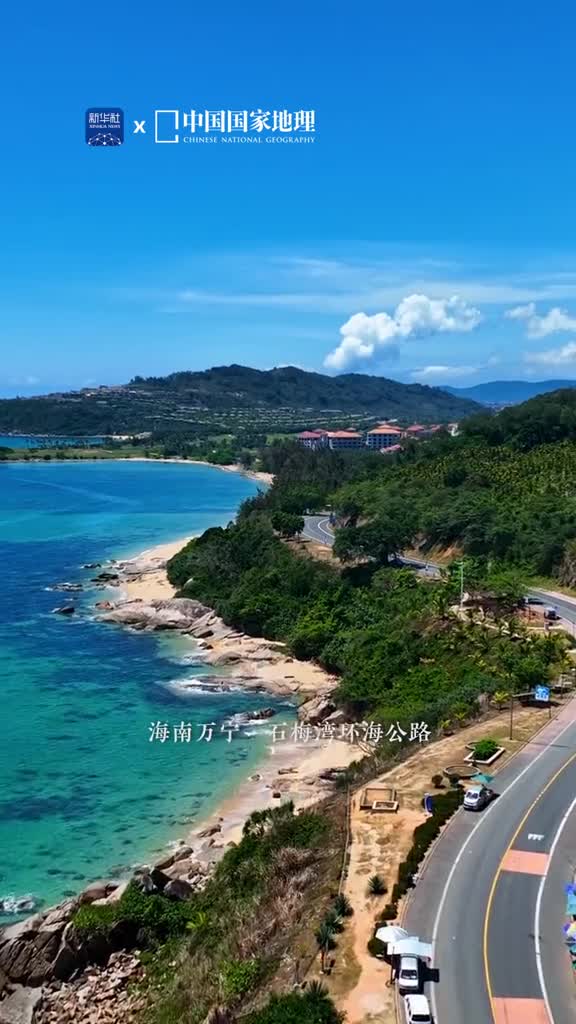 在海南万宁蜿蜒的石梅湾环海公路勾勒出海湾的曲线沿着公路前行一幅幅美丽的画卷展现在眼前碧海蓝天相映成趣壮丽的峭壁倚海而立道路两旁翠绿的枝叶摇曳着仿佛在为每一位行人歌唱美不胜收