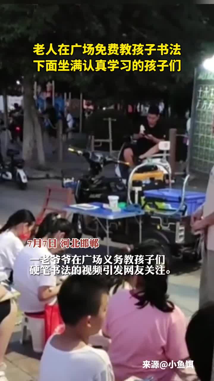 老人在广场免费教孩子书法下面坐满认真学习的孩子们