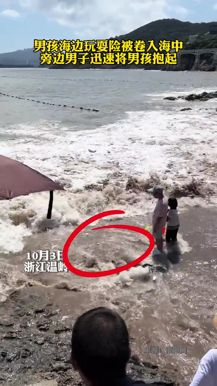 男孩海边玩耍险被卷入海中旁边男子迅速将男孩抱起