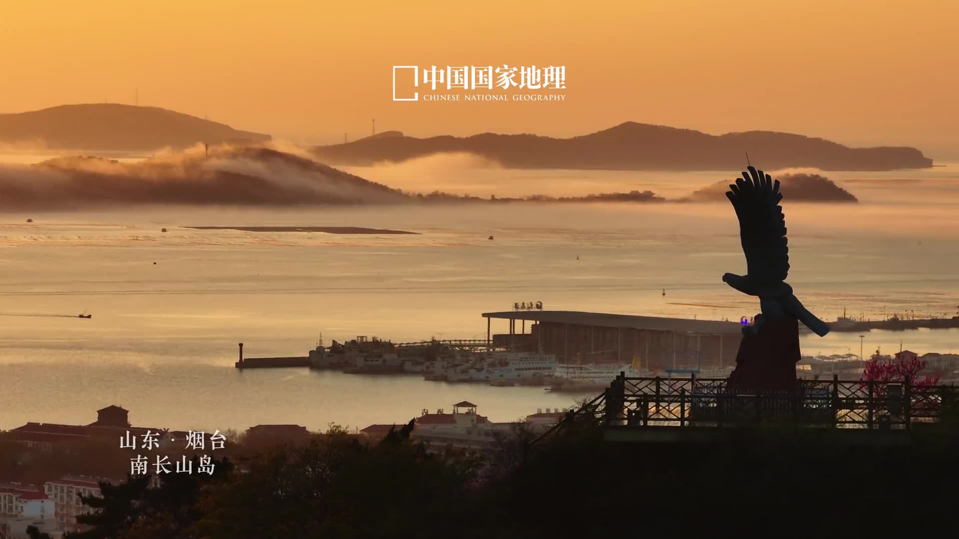 云雾里的海岛如仙山南长山岛位于山东烟台庙岛群岛南部远远望去南北长山岛连成一体宛若连绵起伏的海上山脉因而得名陡峭奇峻的山势诉说着地壳断裂沧海桑田的过往而岛上的雄鹰雕塑傲然矗立在山间激荡四起的浓雾流云中展翅欲飞苍劲有力搏天际