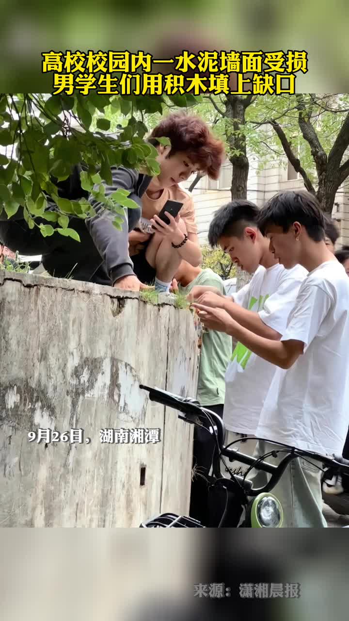 高校校园内一水泥墙面受损男学生们用积木填上缺口