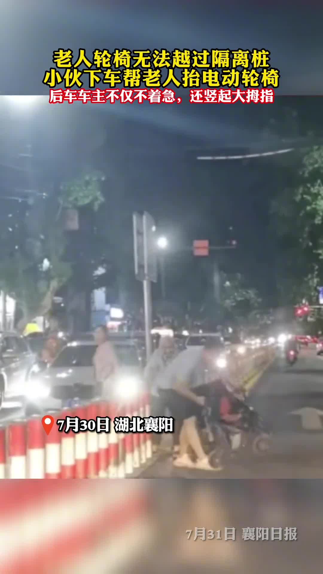 老人轮椅无法越过隔离桩小伙下车帮老人抬电动轮椅后车车主不仅不着急还竖起大拇指
