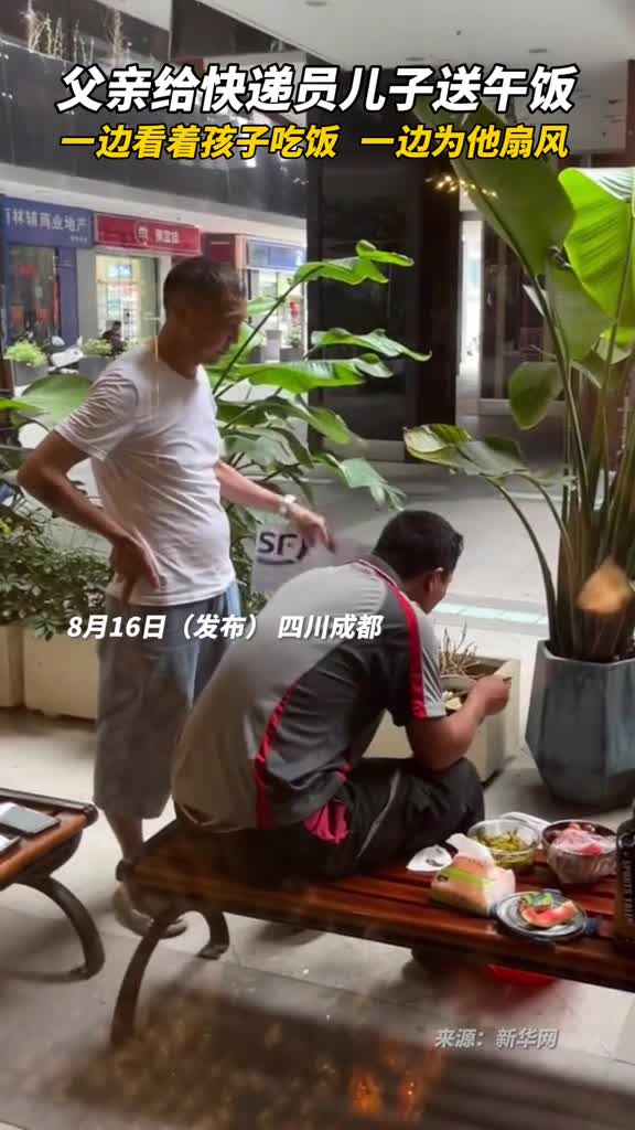 父亲给快递员儿子送午饭一边看着孩子吃饭一边为他扇风
