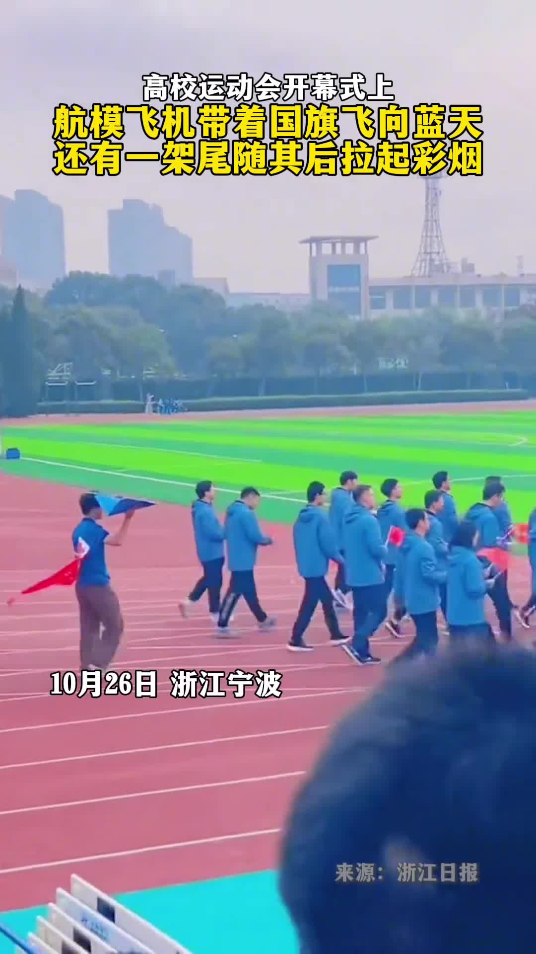 高校运动会开幕式上航模飞机带着国旗飞向蓝天还有一架尾随其后拉起彩烟