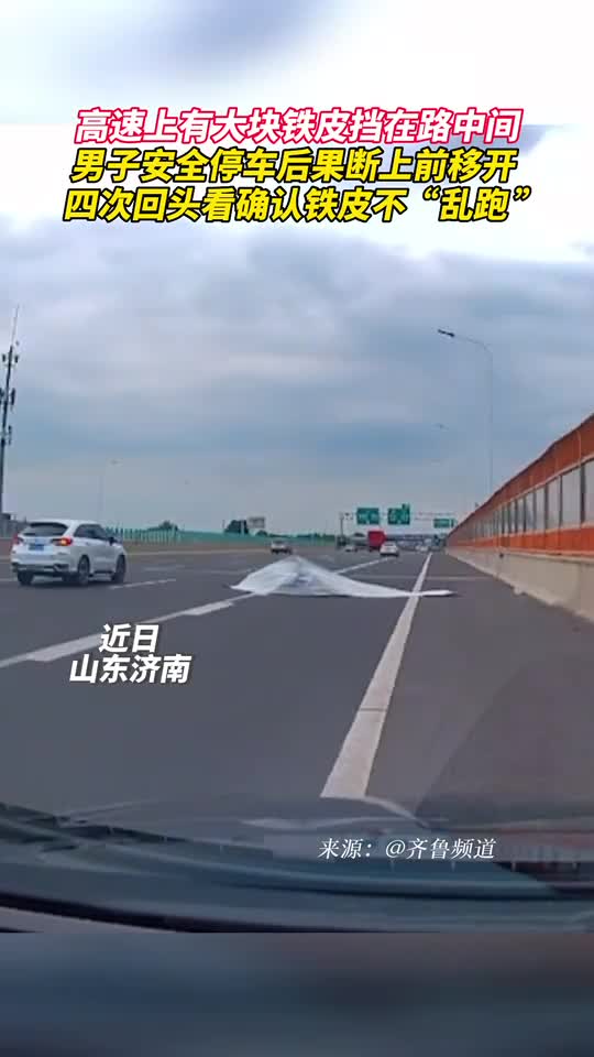 高速上有大块铁皮挡在路中间男子安全停车后果断上前移开四次回头看确认铁皮不乱跑